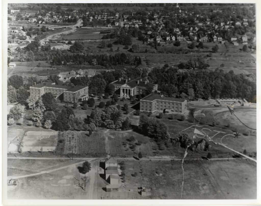 A black and white photo showing an aerial view of the 1928 campus showing Williard, Monroe and the not complete Virginia Hall and a large "FSTC" written on the grass. 