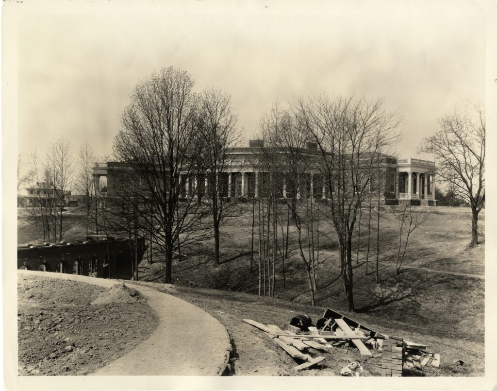 A black and white photo that fits all of Seacobeck Hall taken from Palmieri Plaza showing the bridge across the campus creek.